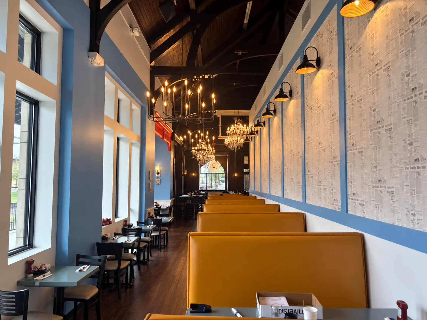 The Morning Post's Lansing dining room, with marigold booths, chandeliers, and a vintage-newsprint accent wall